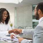 Business partners closing deal in coffee shop. Business man and woman meeting in street cafe and shaking hands with each other. Agreement or handshake concept