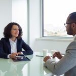 HR manager and applicant meeting for job interview. Business man and woman with tablet sitting at meeting table and talking. Career concept